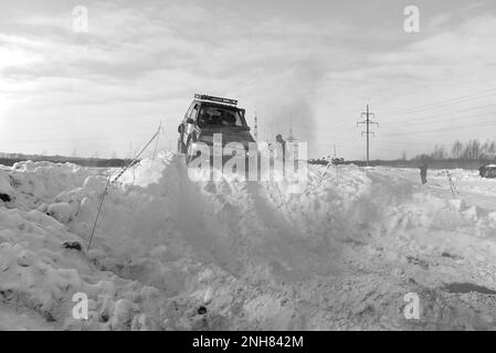 Geländewagen „Suzuki Escudo“ fährt im Geländewagen schnell auf einer verschneiten Straße im braunen Rauch und hebt die Räder eines Schneesturms. Stockfoto