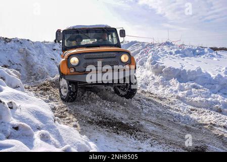 Der russische Offroad-SUV „UAZ Junter 469“ fährt im Geländewagen mit Licht auf einer schwierigen Straße im Schnee im Winter Stockfoto