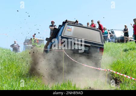 Die Leute sehen sich das Handy aus dem Geländewagen „Jeep Grand Cherokee“, das mit dem Staub von den Rädern auf der Autobahn zum Berg fährt Stockfoto