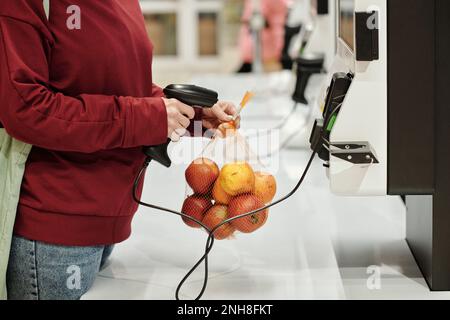 Nahaufnahme von weiblichen Konsumenten im Alltagskleiderpack frischer reifer Äpfel im Supermarkt, um zu erfahren, wie viel Kilogramm Obst kostet Stockfoto