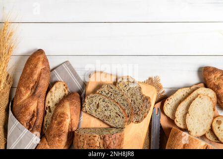 Mit dem Konzept hausgemachter Bäckerei können Sie Multi-Grain-Sauerteig und geschnittenes Baguette auf weißem Holzhintergrund zubereiten Stockfoto