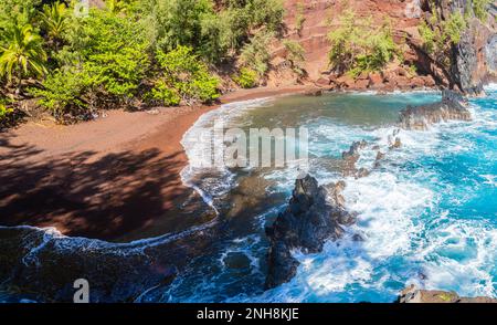 Roter Sand und blaue Wellen am Kaihalulu Beach, Hana, Maui, Hawaii, USA Stockfoto