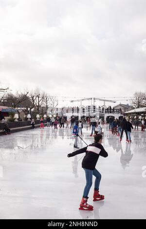 Schlittschuhläufer auf der temporären Eislaufbahn, die vom Rijksmuseum am Museumplein in Amsterdam, Niederlande, errichtet wurde. Stockfoto