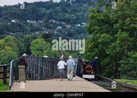 Ein Paar, das mit seinem schmalen Kanalboot am Eingang zum Pontcysyllte Aquädukt vom Trevor-Becken navigiert. Stockfoto