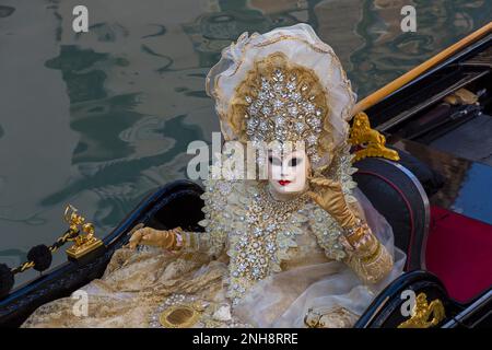 Karnevalsgast gekleidet in prächtigen Kostümen und Maske sitzt während des Karnevals 2023 in Venedig im Februar in San Polo, Venedig, Italien in der Gondel Stockfoto