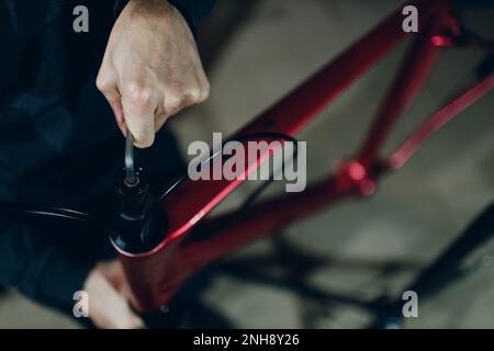 Mechaniker, der mit einem Schraubenschlüssel ein Sonderfahrrad in der Werkstatt zusammenbaut Stockfoto