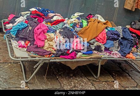 Großer Stapel bunter gebrauchter Kleidung, die auf dem Flohmarkt verkauft wird Stockfoto