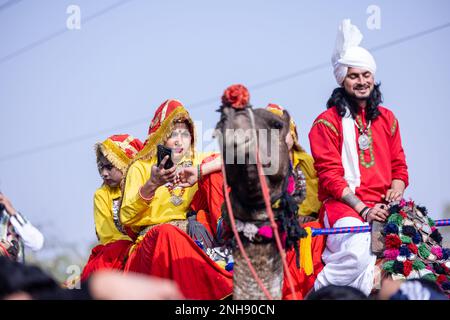 Kamelfestival, Porträt eines jungen Mannes und einer jungen Frau aus Haryana in traditioneller Kleidung, die an der Festumarade auf einem Kamel teilnimmt. Selektiver Fokus. Stockfoto