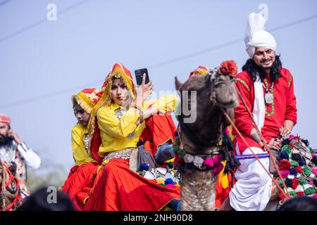 Kamelfestival, Porträt eines jungen Mannes und einer jungen Frau aus Haryana in traditioneller Kleidung, die an der Festumarade auf einem Kamel teilnimmt. Selektiver Fokus. Stockfoto
