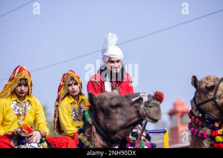 Kamelfestival, Porträt eines jungen Mannes und einer jungen Frau aus Haryana in traditioneller Kleidung, die an der Festumarade auf einem Kamel teilnimmt. Selektiver Fokus. Stockfoto