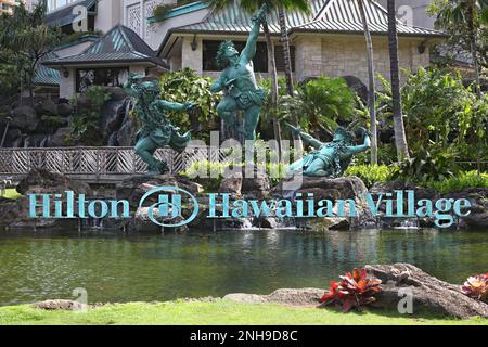Honolulu, Hawaii - 30. März 2020: Verwitterte grüne Kupferstatuen und Namensschild Logo der weltweiten Hotelkette Hilton in Waikikis hawaiianischem Dorf. Stockfoto