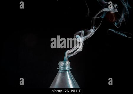 Eine transparente, isolierte Kunststoffflasche, aus der Rauch austritt. Konstruktionselement. Stockfoto