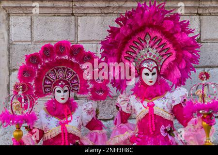 Karnevalsbesucher in prächtigen rosa Kleidern, Kostümen und Masken während des Karnevals 2023 in San Polo, Venedig, Italien im Februar Stockfoto