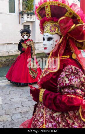 Karnevalsbesucher gekleidet in prächtigen rot-goldenen Kostümen und Maske während des Karnevals 2023 in San Polo, Venedig, Italien im Februar Stockfoto