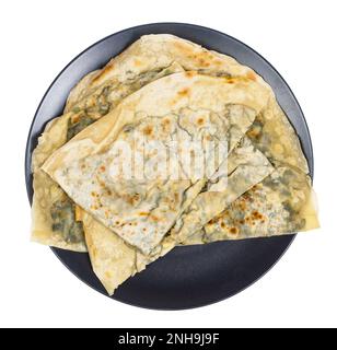 Tatar Cuisine - Blick über Yantik mit Kräutern und Käse (gefüllte gegrillte Küche) auf schwarzem Teller, isoliert auf weißem Hintergrund Stockfoto