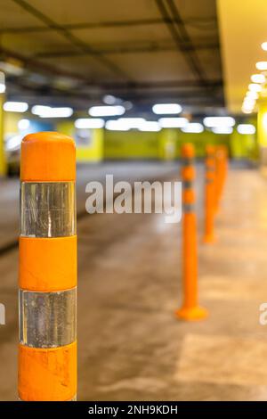 Orangefarbener reflektierender Sicherheitspfosten in Tiefgarage (Fokus auf den ersten Beitrag im Vordergrund) Stockfoto