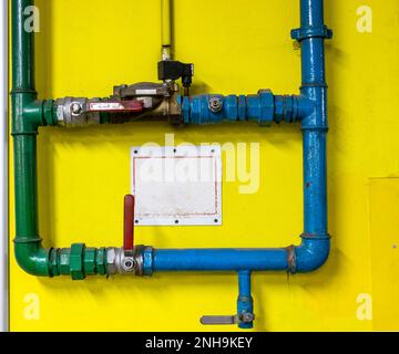 Rohre und Armaturen der automatischen Löschanlage an der gelben Wand der Tiefgarage Stockfoto