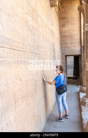 Assuan, Ägypten; 13. Februar 2023 - Eine Frau, die ägyptische Hieroglyphen im Tempel von Philae bewundert, Assuan, Ägypten. Stockfoto