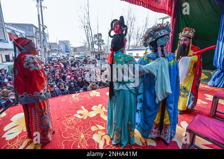 Fuyang, China. 21. Februar 2023. Schauspieler führen „ZhaGuoHuai“ auf, eine traditionelle chinesische Oper, und das Publikum beobachtet sie aufmerksam auf dem Land. Der 2. Tag des 2. Monats des chinesischen Mondkalenders wird als der Tag des „Drachen erhebt seinen Kopf“ bezeichnet. In einigen Teilen Chinas finden traditionelle Volksvorstellungen statt, um diesen Tag zu feiern. Kredit: SOPA Images Limited/Alamy Live News Stockfoto