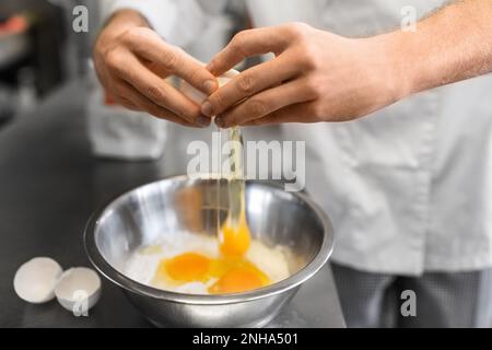 Nahaufnahme des Küchenchefs, der Eier in der Küche zerbricht Stockfoto