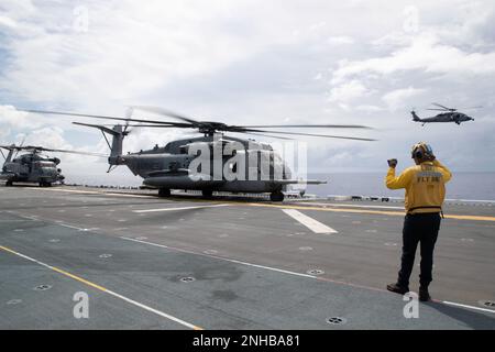 220729-N-XN177-1076 PAZIFIK (29. Juli 2022) – ein MH-60s Sea Hawk Helicopter Assigned to Helicopter Sea Combat Squadron (HSC) 23 fliegt vom amphibischen Angriffsträger USS Tripoli (LHA 7) als CH-53 Super Hallion Helikopter der Marine Medium Tiltrotor Squadron (VMM) 262 (verstärkt) zum Start bereit, 29. Juli 2022. Tripolis ist im US-amerikanischen 7.-Flottengebiet tätig, um die Interoperabilität mit Verbündeten und Partnern zu verbessern und als einsatzbereite Eingreiftruppe zur Verteidigung des Friedens und zur Aufrechterhaltung der Stabilität in der Region Indo-Pazifik zu dienen. Stockfoto