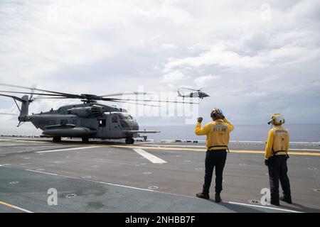 220729-N-XN177-1075 PAZIFIK (29. Juli 2022) – ein MH-60s Sea Hawk Helicopter Assigned to Helicopter Sea Combat Squadron (HSC) 23 fliegt vom amphibischen Angriffsträger USS Tripoli (LHA 7) als ein CH-53 Super Hallion Helikopter der Marine Medium Tiltrotor Squadron (VMM) 262 (verstärkt) startbereit, Juli 29, 2022. Tripolis ist im US-amerikanischen 7.-Flottengebiet tätig, um die Interoperabilität mit Verbündeten und Partnern zu verbessern und als einsatzbereite Eingreiftruppe zur Verteidigung des Friedens und zur Aufrechterhaltung der Stabilität in der Region Indo-Pazifik zu dienen. Stockfoto