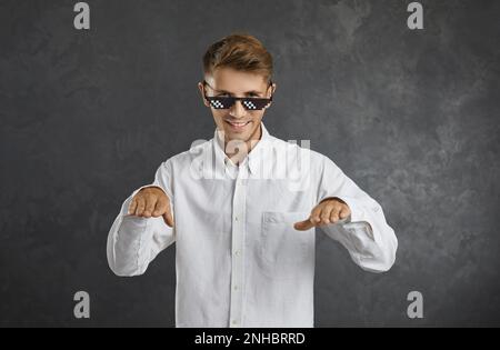Ein lustiger, glücklicher, selbstbewusster junger Mann im Hemd und mit einer Brille, der tanzt und Spaß hat Stockfoto