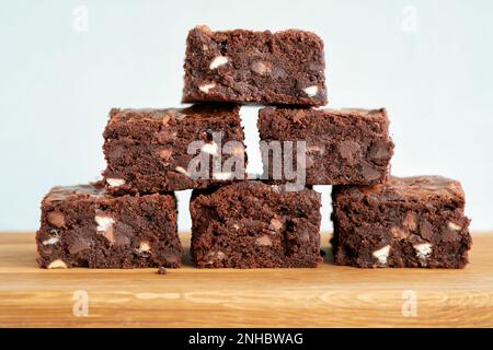 Eine Charge frisch gebackener dreifach-Schokoladen-Brownies auf einem hölzernen Servierbrett. Die Brownies sind noch warm und klebrig. Ein Genuss Stockfoto