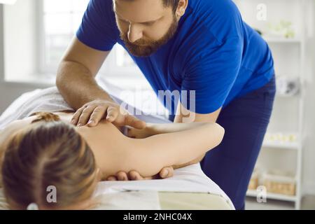 Professioneller männlicher Masseur Therapeut führt therapeutische Körpermassage für junge Frau durch. Stockfoto