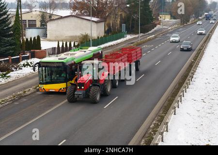 Verkehr auf der Autobahn. Ein Bus, ein Traktor, Lastwagen und Autos fahren auf dem Weg. Stockfoto