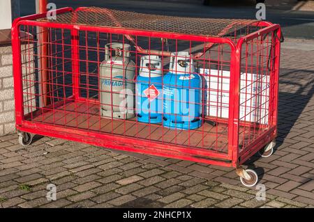 Drei kleine Gasflaschen in einem roten Stahlkäfig Stockfoto