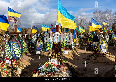 Blaue und gelbe ukrainische Nationalflaggen werden vom Wind geweht, und Blumen liegen auf Gräbern von Soldaten, die innerhalb eines Jahres des Kampfes mit russischen Streitkräften getötet wurden, auf dem Friedhof von Lisove in Kiew, der Hauptstadt der Ukraine am 21. Februar 2023. Familien und Freunde des getöteten Soldaten hinterlassen die Flaggen als patriotischen Akt. Da sich die Invasion der Ukraine durch die russischen Streitkräfte ihrem ersten Jahrestag nähert, ist die Zahl der Opfer sehr hoch, obwohl die genauen Zahlen unbekannt sind. Mindestens 13 ukrainische Soldaten verloren ihr Leben (Foto: Dominika Zarzycka/Sipa USA) Stockfoto