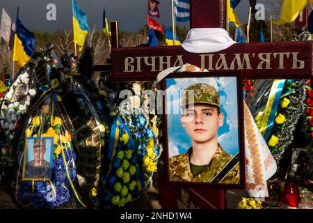 Bilder von Soldaten, blaue und gelbe ukrainische Nationalflaggen und Blumen liegen auf Gräbern von Soldaten, die innerhalb eines Jahres des Kampfes mit russischen Streitkräften auf dem Friedhof von Lisove in Kiew, der Hauptstadt der Ukraine am 21. Februar 2023, getötet wurden. Familien und Freunde des getöteten Soldaten hinterlassen die Flaggen als patriotischen Akt. Da sich die Invasion der Ukraine durch die russischen Streitkräfte ihrem ersten Jahrestag nähert, ist die Zahl der Opfer sehr hoch, obwohl die genauen Zahlen unbekannt sind. Mindestens 13 ukrainische Soldaten verloren ihr Leben (Foto: Dominika Zarzycka/Sipa USA) Stockfoto