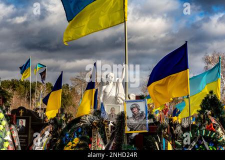 Blaue und gelbe ukrainische Nationalflaggen werden vom Wind geweht, und Blumen liegen auf Gräbern von Soldaten, die innerhalb eines Jahres nach dem Kampf mit russischen Truppen auf dem Friedhof von Lisove in Kiew, der Hauptstadt der Ukraine am 21. Februar 2023, getötet wurden. Familien und Freunde des getöteten Soldaten hinterlassen die Flaggen als patriotischen Akt. Da sich die Invasion der Ukraine durch die russischen Streitkräfte ihrem ersten Jahrestag nähert, ist die Zahl der Opfer sehr hoch, obwohl die genauen Zahlen unbekannt sind. Mindestens 13 ukrainische Soldaten verloren ihr Leben (Foto: Dominika Zarzycka/Sipa USA) Stockfoto