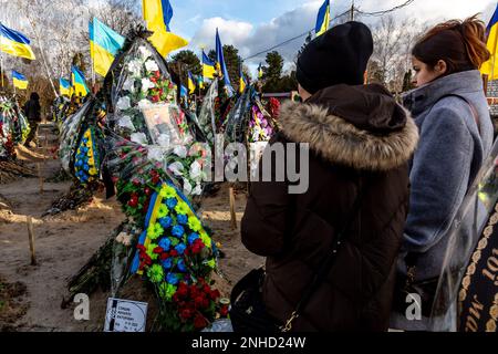 Kiew, Ukraine. 21. Februar 2023. Die Frau eines gefallenen Soldaten (links), der im Januar 2023 starb, besucht sein Grab auf dem Friedhof von Lisove in Kiew, der Hauptstadt der Ukraine am 21. Februar 2023. Familien und Freunde des getöteten Soldaten hinterlassen die Flaggen als patriotischen Akt. Da sich die Invasion der Ukraine durch die russischen Streitkräfte ihrem ersten Jahrestag nähert, ist die Zahl der Opfer sehr hoch, obwohl die genauen Zahlen unbekannt sind. Mindestens 13 ukrainische Soldaten verloren ihr Leben (Foto: Dominika Zarzycka/Sipa USA) Kredit: SIPA USA/Alamy Live News Stockfoto