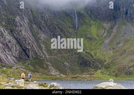 Walkers Approach the Devils Kitchen, Llyn Idwal, Ogwen Valley, Wales, UK. Ein herrlicher Spaziergang in Richtung der beeindruckenden Felswand Stockfoto