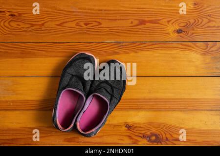 Graue, dreckige Sportschuhe für Damen zu Hause stehen auf dem Holzboden, Frauen Sportschuhe Stockfoto