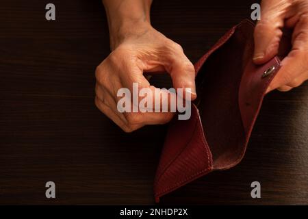 Die Hände einer alten Frau öffneten ihre leere Brieftasche auf dem Hintergrund Stockfoto