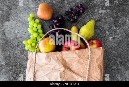Blick von oben auf frische Bio-Früchte aus der Region in braunem Papier Tasche auf Stein Hintergrund Stockfoto