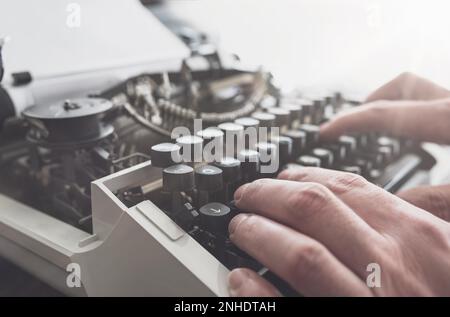 Nahaufnahme des Mannes, der auf der Tastatur des alten Handbuchs tippt Schreibmaschine Stockfoto