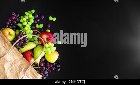 Direkt über Schuss von frischen Bio-Obst aus der Region in braun Papiertüte auf dunklem Hintergrund Stockfoto