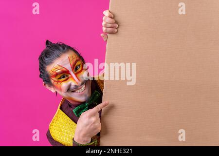 Clown mit weißer Gesichtsmaske, mit einem Schild auf pinkfarbenem Hintergrund, mit der Spitze Stockfoto