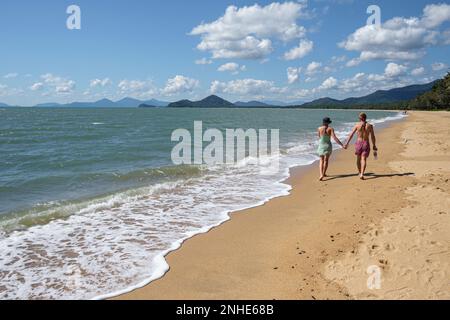Ein junges Paar geht Hand in Hand am Strand von Palm Cove, Queensland, Australien entlang Stockfoto