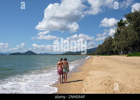 Ein junges Paar geht Hand in Hand am Strand von Palm Cove, Queensland, Australien entlang Stockfoto