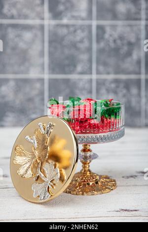 Farbenfrohe Süßigkeiten; Erdbeerbonbons in stilvoller Zuckerschale auf weißem Holztisch. Süßigkeiten in einer luxuriösen Zuckerschüssel mit weißem Holzboden. Stockfoto