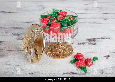 Farbenfrohe Süßigkeiten; Erdbeerbonbons in stilvoller Zuckerschale auf weißem Holztisch. Süßigkeiten in einer luxuriösen Zuckerschüssel mit weißem Holzboden. Stockfoto