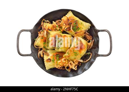 Gebratene schwäbische Fleischravioli (sogenannte Maultaschen) mit gerösteten Zwiebeln, serviert in einer eisernen Bratpfanne auf weißem Hintergrund Stockfoto