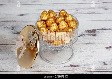 Mit Gelatine beschichtete Schokolade in luxuriösen Süßigkeiten-Schüsseln. Schokolade in einer luxuriösen Zuckerschüssel mit weißem Holzhintergrund. Stockfoto
