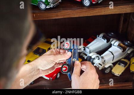 Ein Mann, der eines seiner vielen alten Miniaturautos bewundert Stockfoto