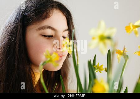 Nahaufnahme eines dunkelhaarigen Mädchens, das Narzissenblüten sieht Stockfoto